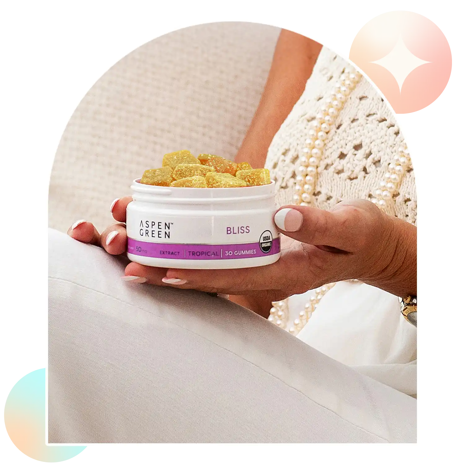 Hand holding a container of Aspen Green Bliss CBD Gummies with a blurred background.