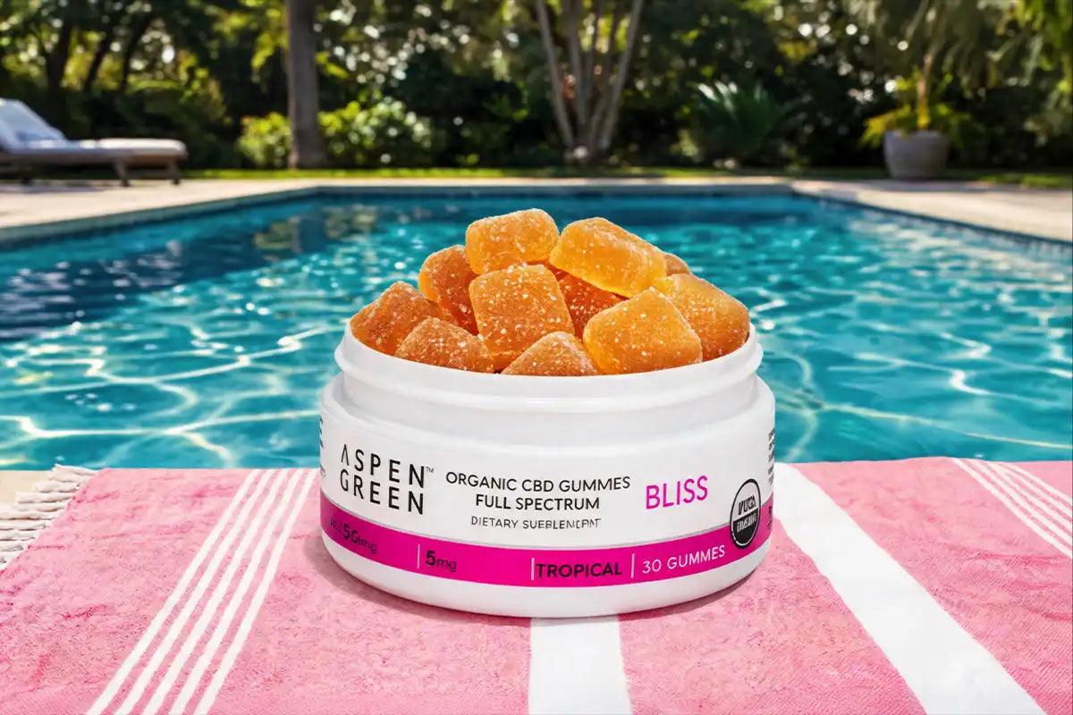 Jar of Aspen Green Bliss gummies on a poolside towel with a pool