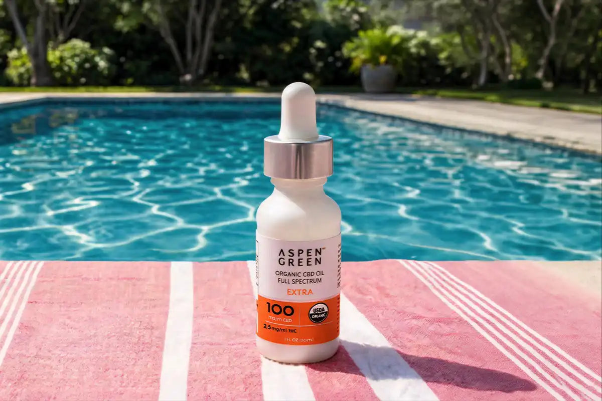 Aspen Green CBD oil bottle on a towel by a pool
