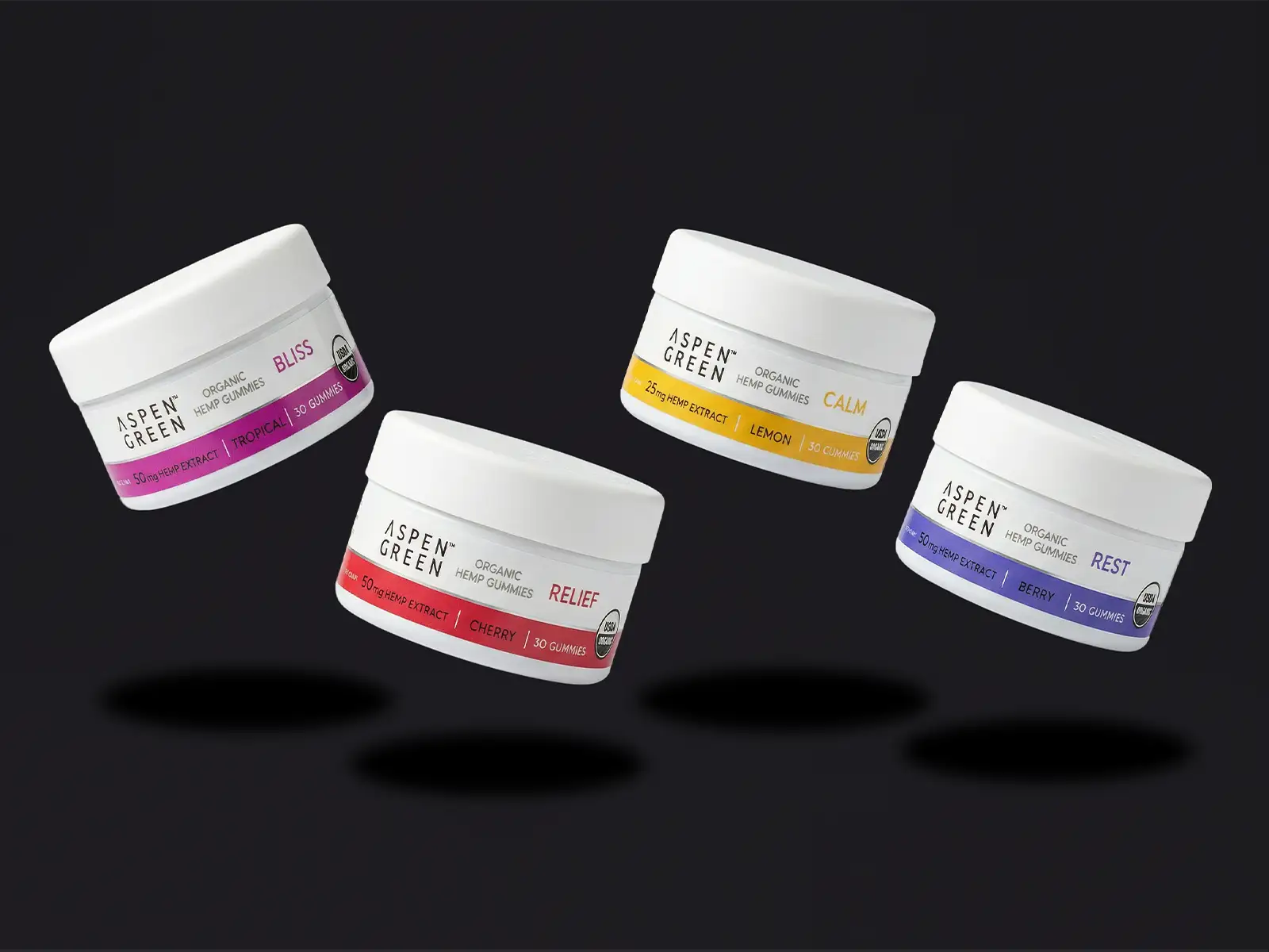 Four jars of Aspen Green CBD gummies on a black background