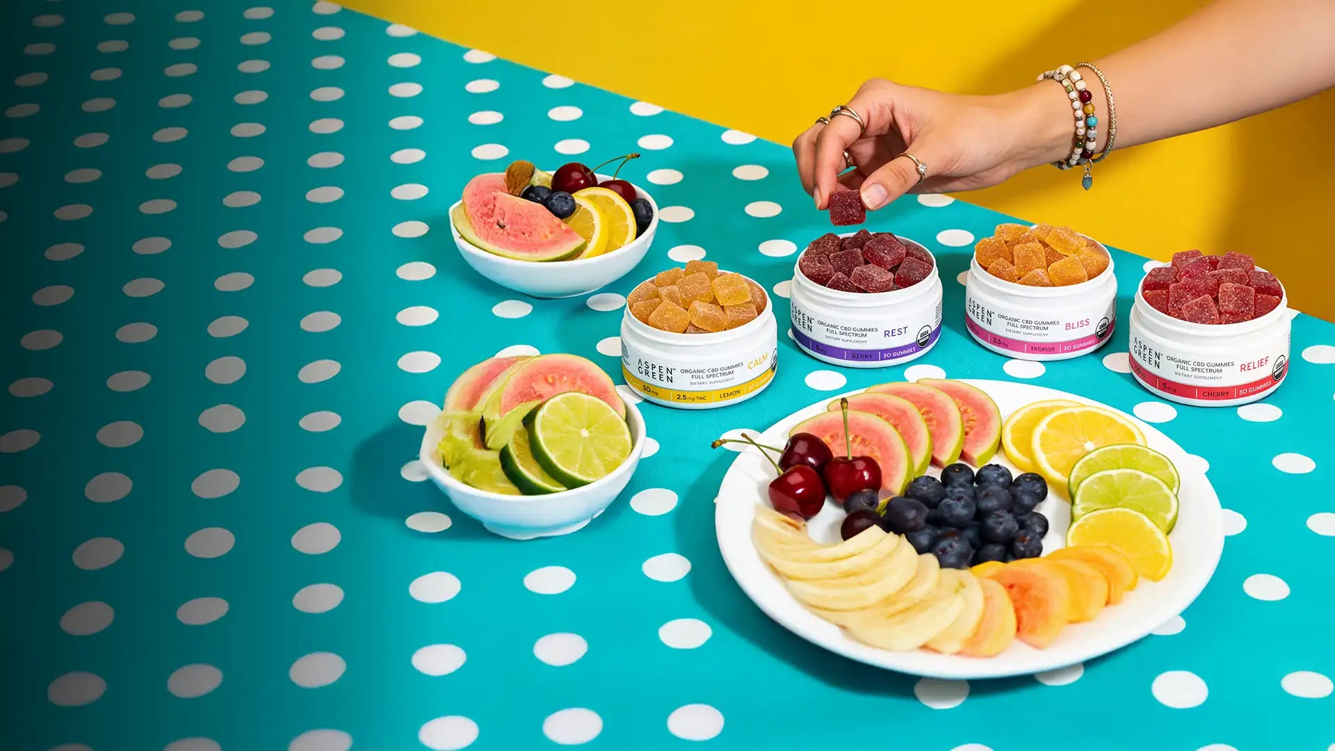 Aspen Green CBD gummies arranged on a retro polka dot table with fruit, promoting organic full spectrum hemp gummies.