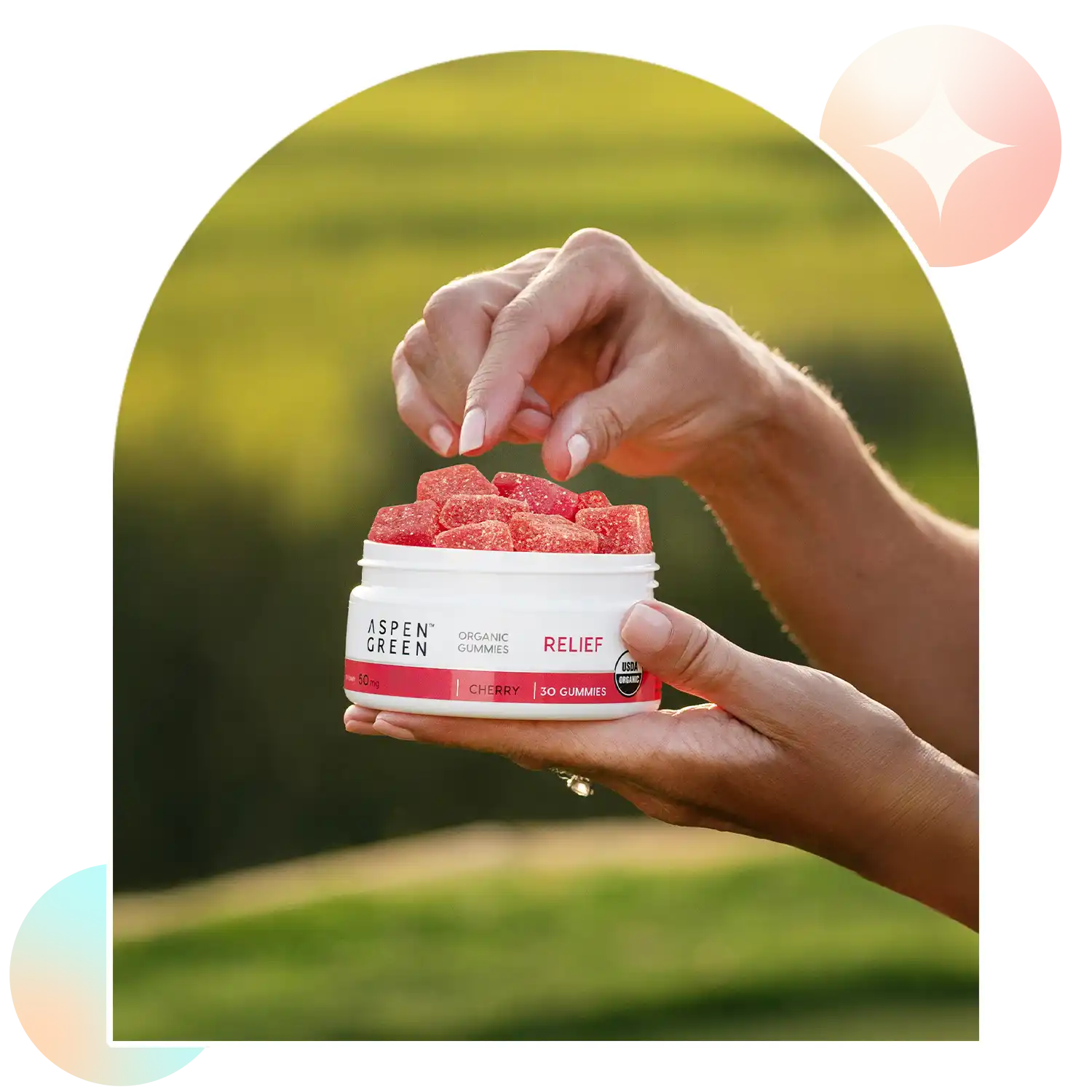Woman taking an Aspen Green Relief CBD gummy from an open jar with a blurred outdoor background.
