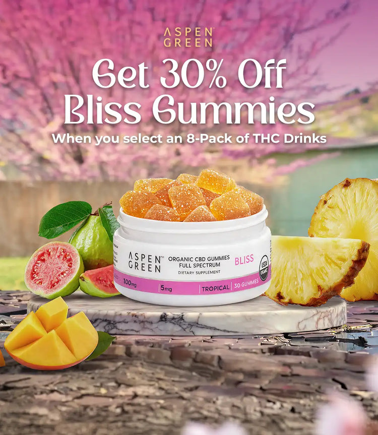 Promotional banner for Aspen Green Bliss Gummies with a jar of gummies, fruits, and a pineapple on a wooden surface.