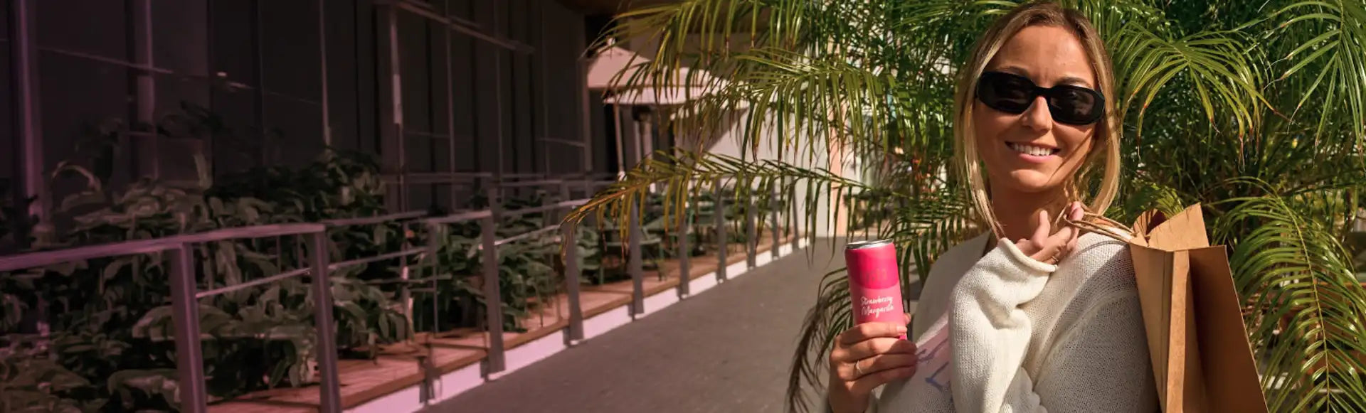 Woman holding a Strawberry Margarita can and shopping bag