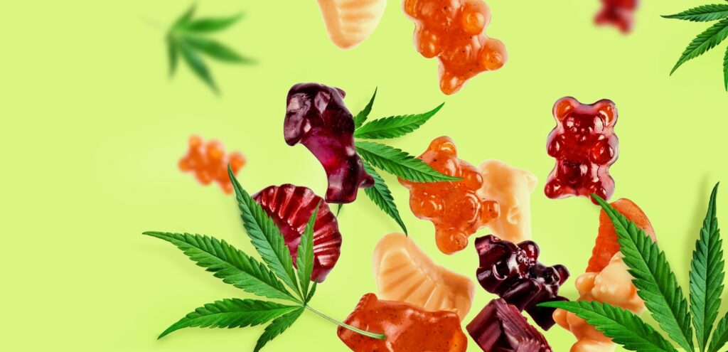 Colored gummies fly along with cannabis leaves.