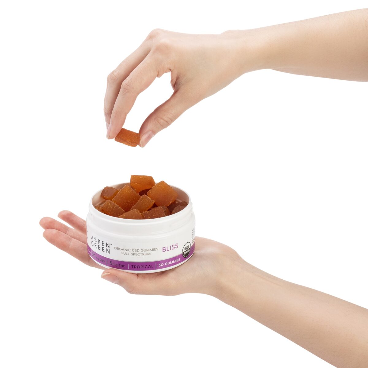 Aspen Green USDA Certified Organic CBD Gummies in open jar with hand holding gummy, Bliss (50mg CBD), Tropical Flavor