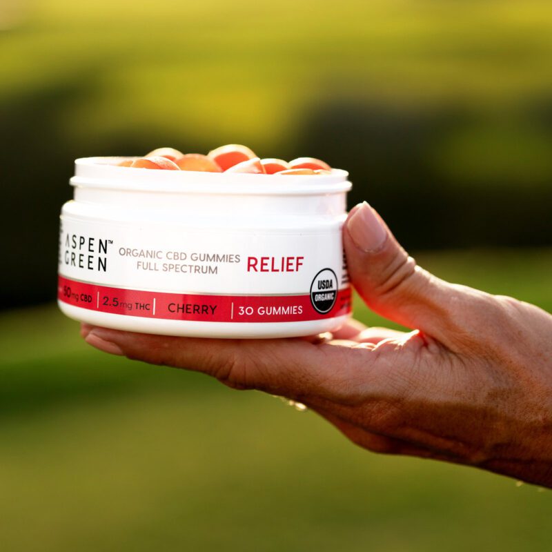 Hand holding Aspen Green CBD relief gummies container