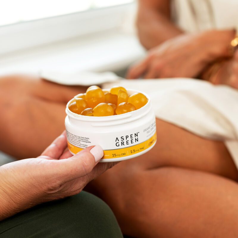 Hand offering container of Aspen Green CBD calm gummies