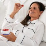 Woman eating Aspen Green rest gummies in bed