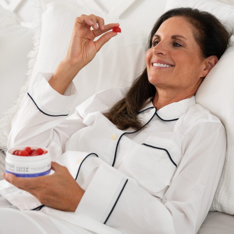 Woman eating Aspen Green rest gummies in bed