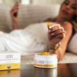 Woman grabbing Aspen Green CBD calm gummy on couch