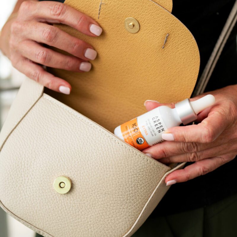 Woman putting Aspen Green Extra Citrus CBD Oil in purse