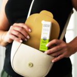 Woman putting Aspen Green Extra Unflavored CBD Oil box in purse