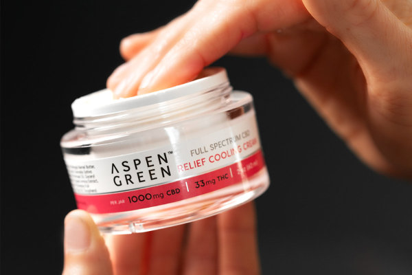 Hand taking Aspen Green Relief Cooling Cream from jar